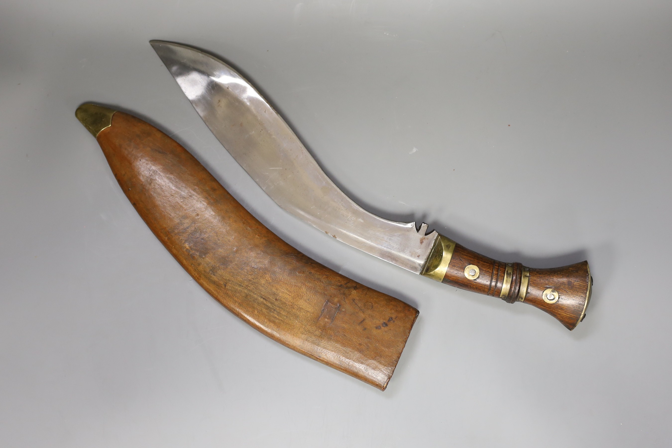 A large Kukri in with brass mounted wooden handle and leather wooden case, 54cm long